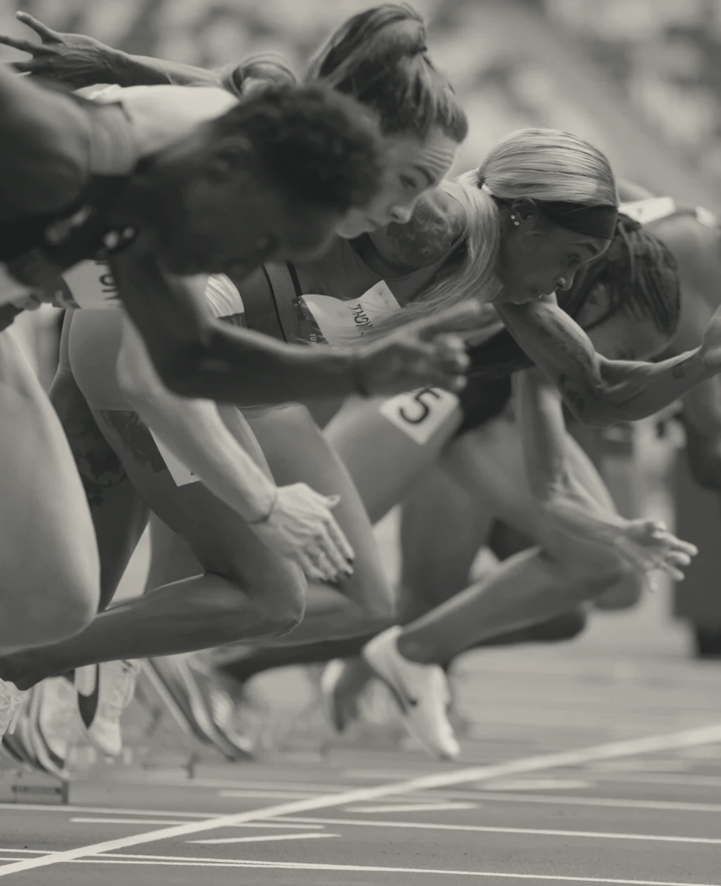 Track athletes sprinting together at the start of a race